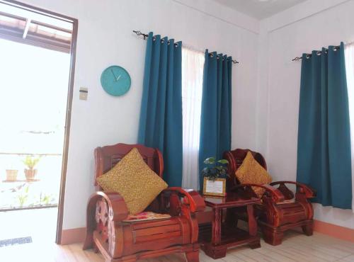 two chairs in a living room with blue curtains at RM3 - Ground Floor Unit in San Roque Bauan Batangas in Batangas City