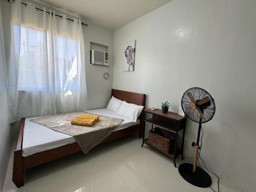 a small bedroom with a bed and a fan at Summer10th Verdant Palawan in Puerto Princesa City