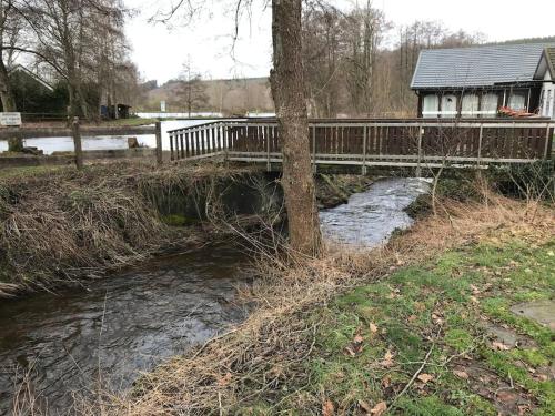 a bridge over a river with a house in the background at Chalet am Weiher in Recht
