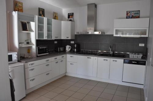a white kitchen with white cabinets and appliances at La cadole de Clem in Juliénas