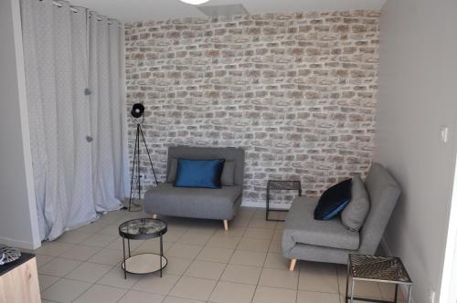 a living room with two chairs and a brick wall at La cadole de Clem in Juliénas