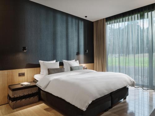 a bedroom with a large bed and a large window at La Butte aux Bois a Small Luxury Hotel of the World in Lanaken