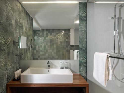 a bathroom with a white sink and a shower at La Butte aux Bois a Small Luxury Hotel of the World in Lanaken