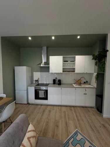 una cocina con armarios blancos y un sofá en una habitación en La chambre vert, en Amiens