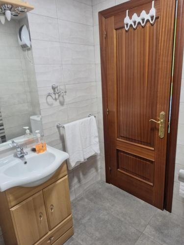 a bathroom with a sink and a wooden door at Jardines in O Barco de Valdeorras