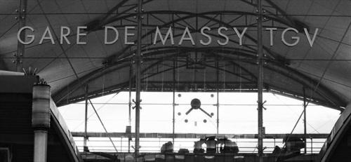 a black and white photo of a train station with a clock at Studio Suite Massy Atlantis TGV in Massy