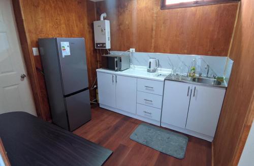 a small kitchen with a refrigerator and a sink at Bosque Valdiviano Apartment in Valdivia