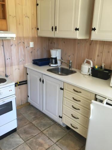 a kitchen with white cabinets and a sink at Rønlund Hyttepark, Midt-i-garde in Ron