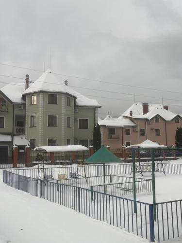 a fence in front of a building with snow at Moonglade Allure Houses in Polyana