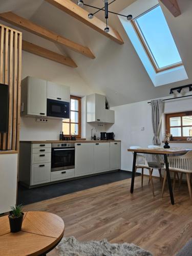 a large kitchen with white cabinets and a table at Pod vinohradem - apartmány & vinné sklepy in Mutěnice