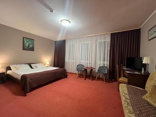une chambre d'hôtel avec un lit, une table et des chaises dans l'établissement Hotel Kłodzko, à Kłodzko