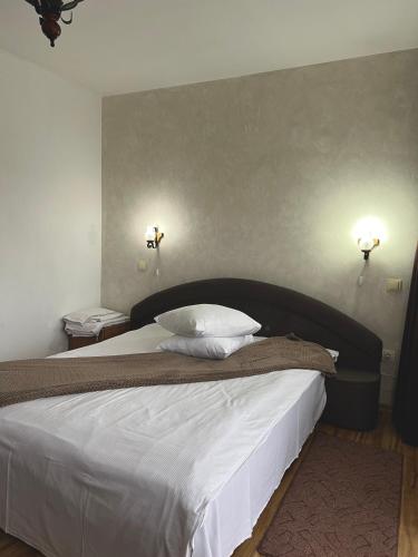 a bedroom with a large bed with two lights on the wall at Pensiunea Irina Maramureș in Deseşti