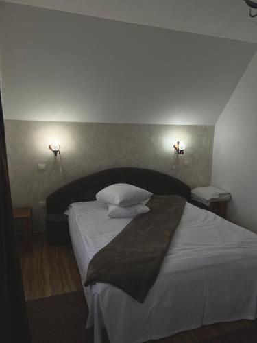 a bedroom with a bed with white sheets and pillows at Pensiunea Irina Maramureș in Deseşti