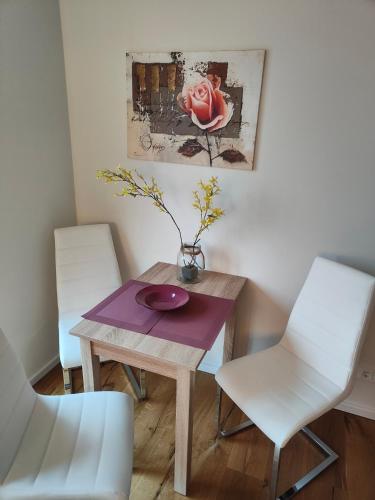 a table with two chairs and a vase on it at Ferienwohnungen - barrierefrei - im sanierten Gutshof in Lalendorf