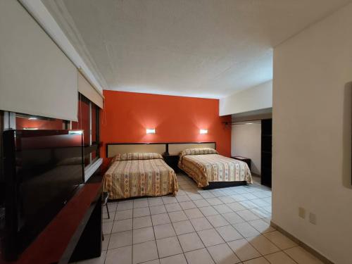 2 camas en una habitación de hotel con paredes de color naranja en Hotel Montreal en León