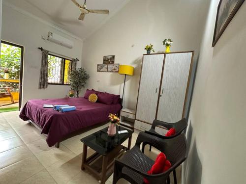 a bedroom with a purple bed and a chair at Cool viva Goa villa near beach in Colva