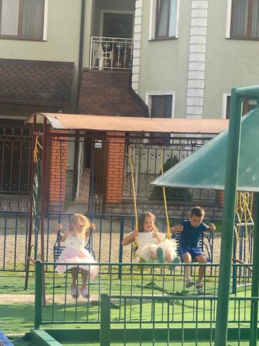 two children sitting on swings at a playground at Moonglade Allure Houses in Polyana
