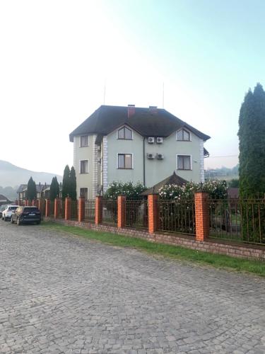 a white house behind a fence on a street at Moonglade Allure Houses in Polyana