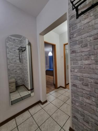 uma casa de banho com uma parede de tijolos e um espelho. em Pokoje AK53 em Częstochowa