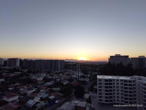 a city skyline with the sun setting in the distance at Apartamento La Florida Mirador in Santiago