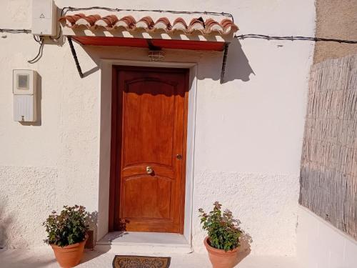 a wooden door on a white building with two potted plants at Casa nuestro sueño in Partaloa