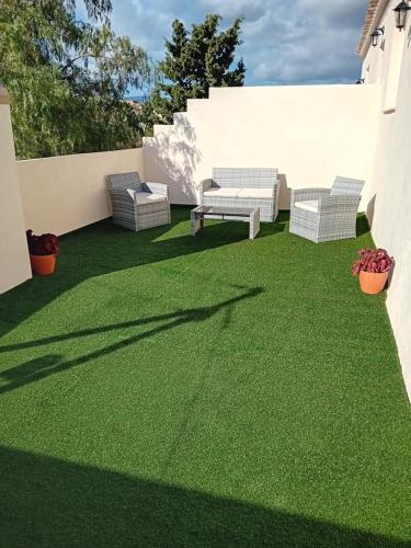a patio with green grass and two chairs on it at Casa nuestro sueño in Partaloa