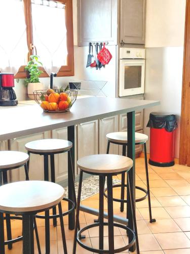 une cuisine avec des tabourets et un comptoir avec un bol de fruits dans l'établissement Le Nid, à Villecroze