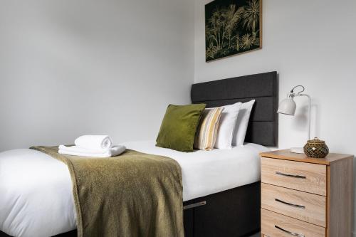 um quarto com uma cama com lençóis brancos e uma mesa de cabeceira em Sunbeam cottage contractor Parking WiFi Garden em Colchester