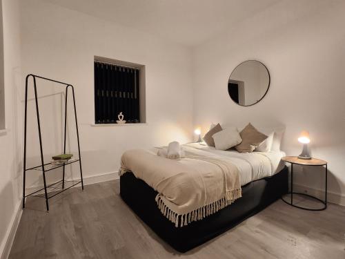 ein Schlafzimmer mit einem Bett mit zwei Lampen und einem Spiegel in der Unterkunft ApartHotel Flat 1 - 10 min to centre by Property Promise in Cardiff