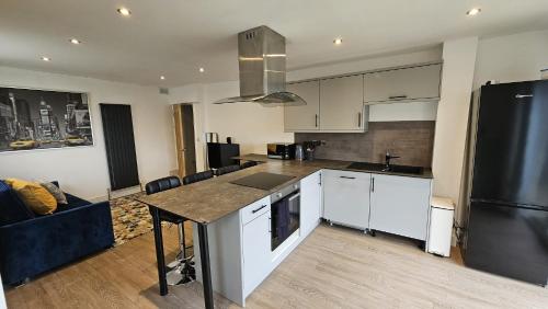 uma cozinha com armários brancos e um frigorífico preto em Cosy Corner Suite em Bradford