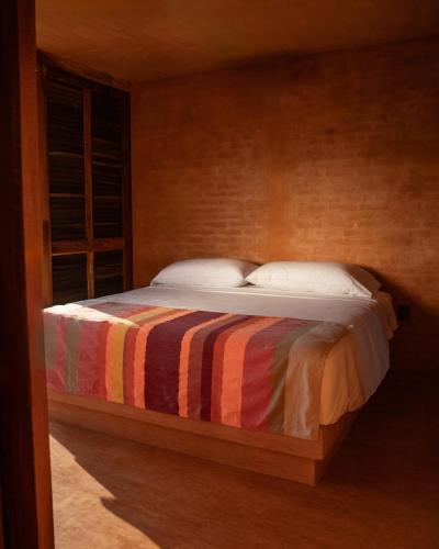 a bedroom with a bed with a striped blanket at Mazul Puerto Escondido in Tlachicón