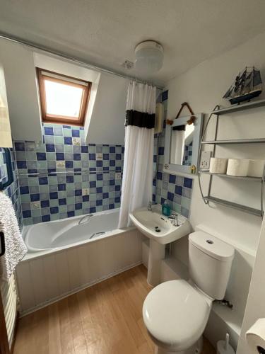a bathroom with a toilet and a tub and a sink at Runaway Cottage, Whitby in Whitby