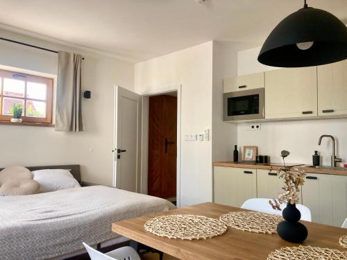 a bedroom with a bed and a table and a kitchen at Pod vinohradem - apartmány & vinné sklepy in Mutěnice