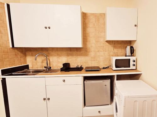 a kitchen with white cabinets and a microwave at studio in Ayia Napa
