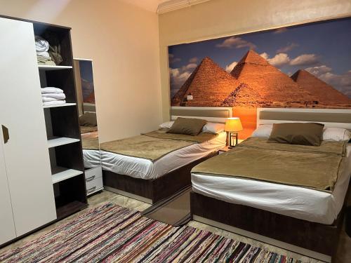 開羅的住宿－Matto Pyramids Inn，一间卧室设有两张床和金字塔壁画。