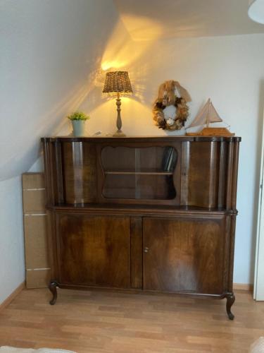 a wooden entertainment center with a lamp on top of it at Lütte Stuv in Kollmar