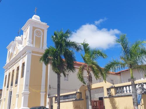 un edificio con una torre de reloj y palmeras en Will's House, en São Luís
