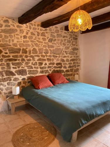 un lit dans une chambre avec un mur en pierre dans l'établissement Maison de campagne, Au 40, Morvan, Bourgogne, à La Comelle