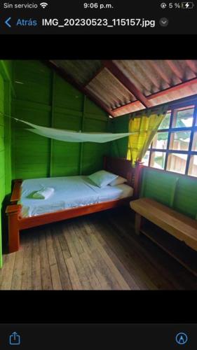 Habitación verde con cama y banco en Posada jurubira en Juruvidá
