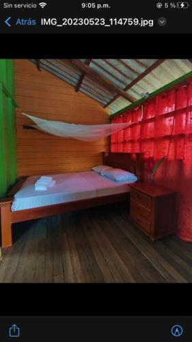 a room with a bed with a red wall at Posada jurubira in Juruvidá