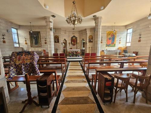 a church with wooden tables and chairs and a chandelier at St Thomas Home's Guesthouse - Jerusalem in Jerusalem
