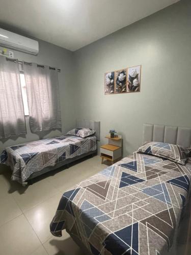 a bedroom with two beds and a picture on the wall at Casa inteira em Nova Mutum in Nova Mutum