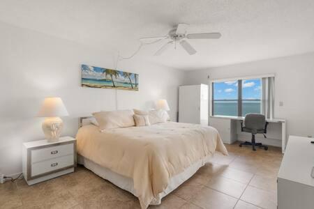 Schlafzimmer mit einem Bett, einem Schreibtisch und einem Fenster in der Unterkunft Beachfront Condo with Pool and Hot Tub Reflections On The Gulf 504 in Clearwater Beach