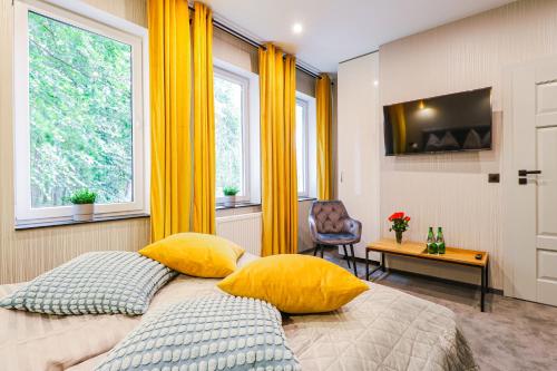 a bedroom with yellow curtains and a bed with yellow pillows at modrakvillapark in Parłowo