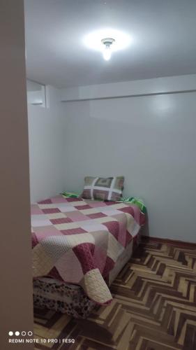 ein Schlafzimmer mit einem Bett mit einer karierten Decke in der Unterkunft Antawara in Puno