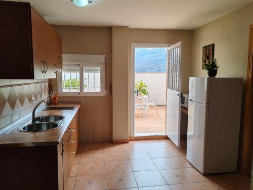 a kitchen with a white refrigerator and a door to a patio at Ruralguejar in Güéjar-Sierra