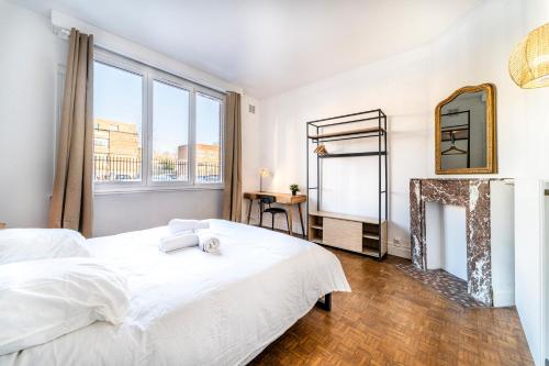 ein Schlafzimmer mit einem großen weißen Bett und einem Kamin in der Unterkunft T2 Jardin Privé - Lille Europe in Lille