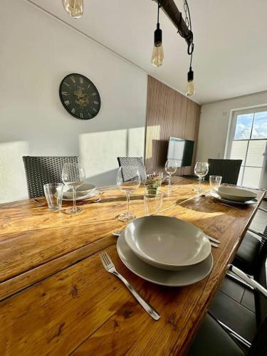 una mesa de madera con platos y copas de vino. en Stilvoll eingerichtetes Ferienhaus in ruhiger Lage en Bremerhaven