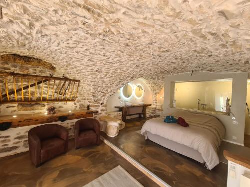 1 dormitorio con cama y pared de piedra en Gîtes 2 adultes dans un mas charme et calme assuré, en Servas
