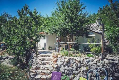 a house with a stone fence and a stone wall at Robinson Haus Ivan No Electricity in Makarska